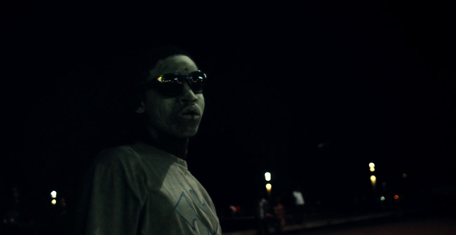 a man wearing sunglasses standing in the dark