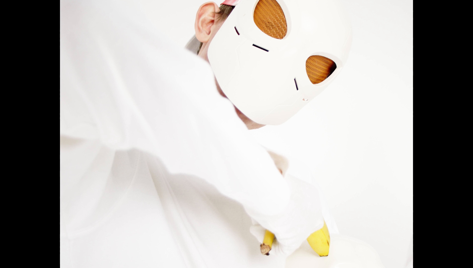 a person wearing a white mask with a banana sticking out of it