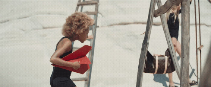 a woman climbing up a ladder with a red box