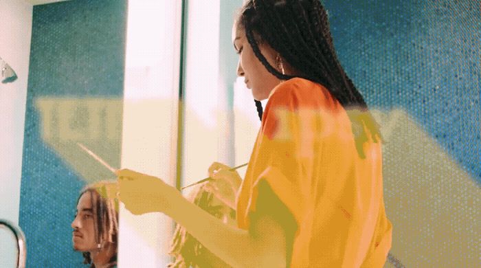 a woman brushing her hair in front of a mirror