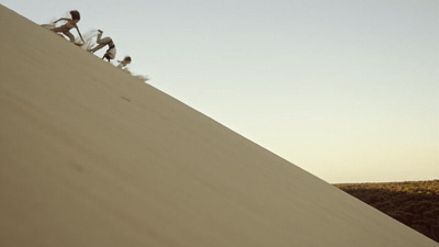 a group of people climbing up the side of a sand dune