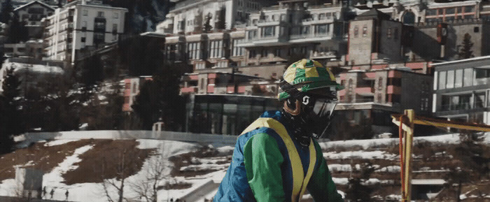 a man wearing a helmet and goggles standing in front of a building