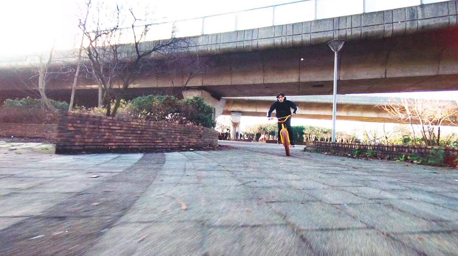 a man riding a skateboard down a street under a bridge