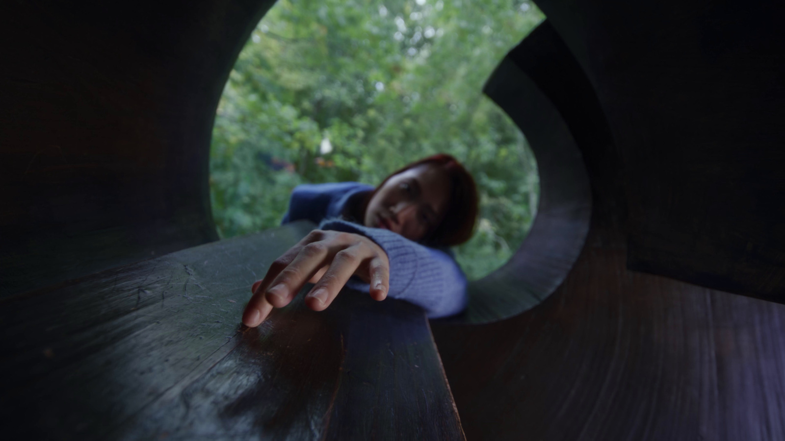 a woman leaning on a wooden bench in a park