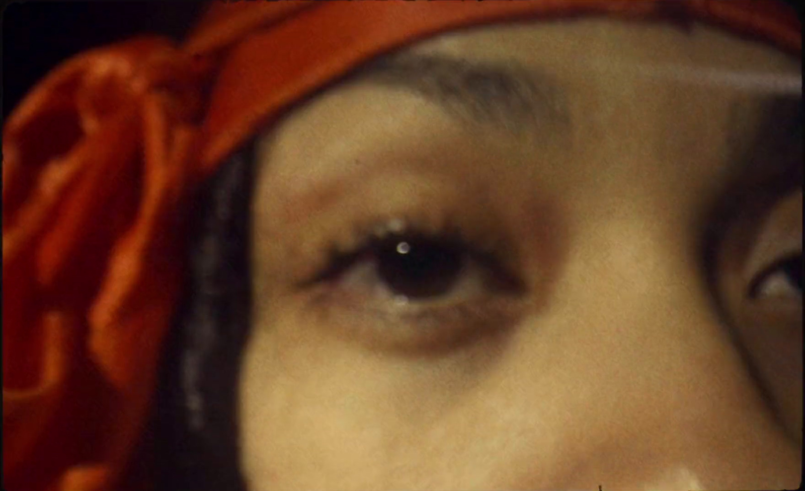 a close up of a woman's eye with a red scarf around her head