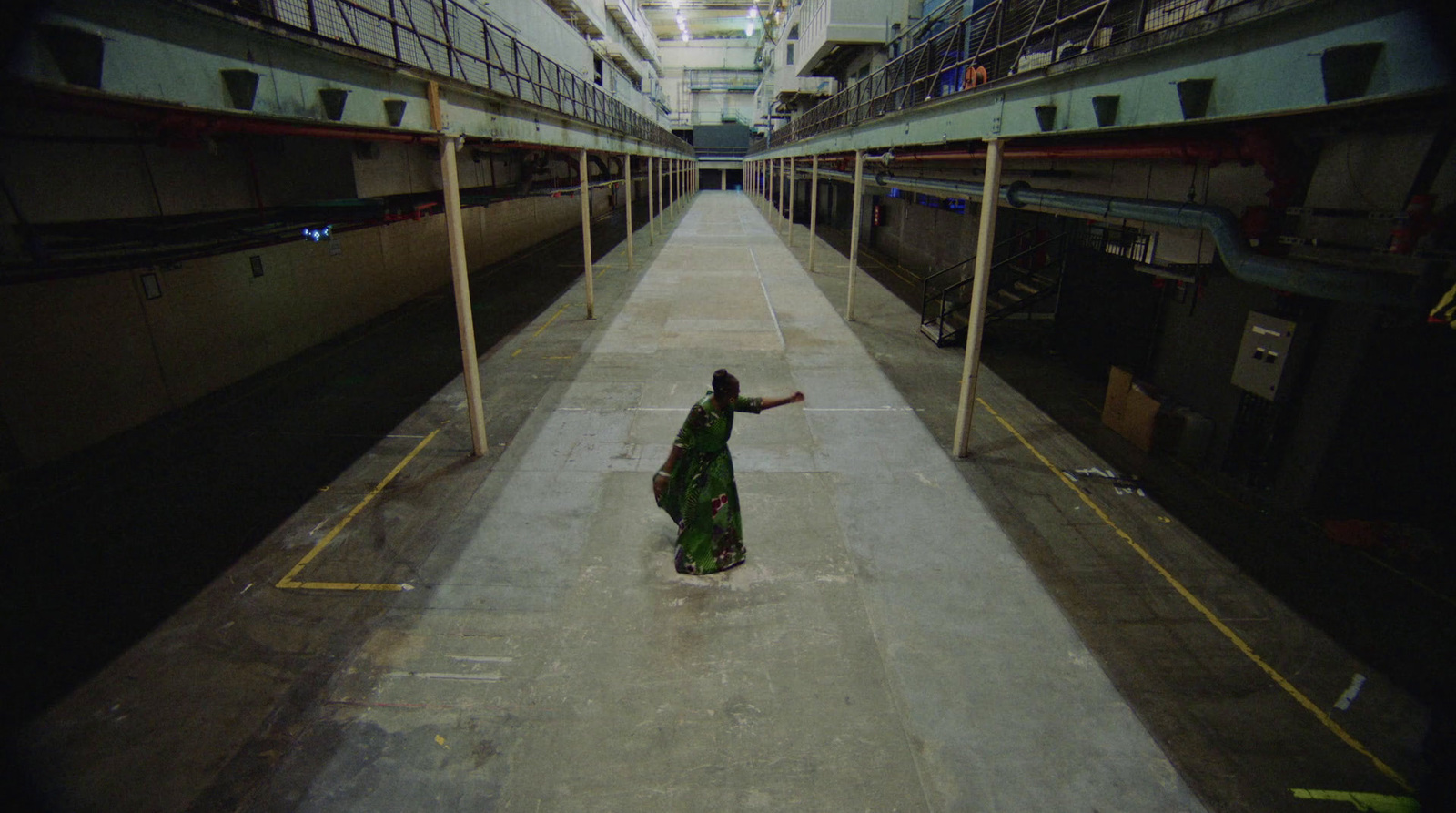 a woman in a long green dress walking down a hallway