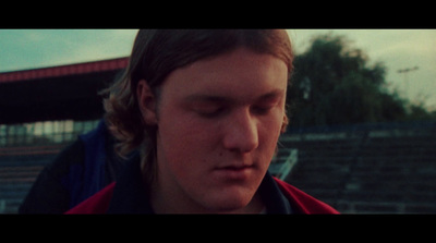 a man with his eyes closed standing in front of a stadium