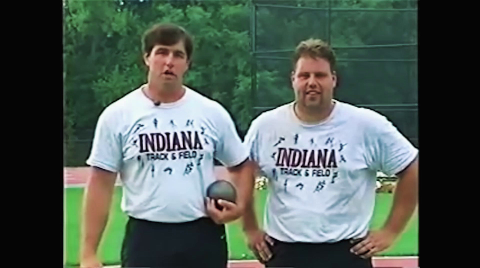 two men standing next to each other holding a ball