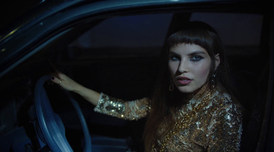 a woman sitting in a car with her hand on the steering wheel