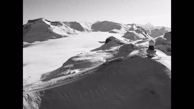 a man riding a snowboard down the side of a snow covered mountain