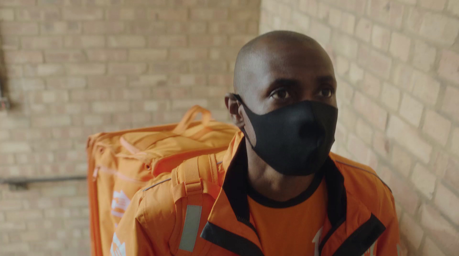 a man wearing an orange jacket and a black mask