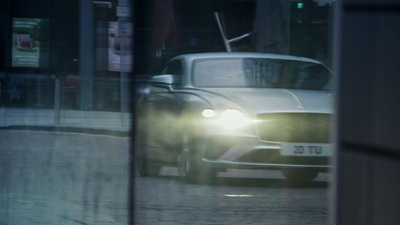 a car driving down a street next to a tall building