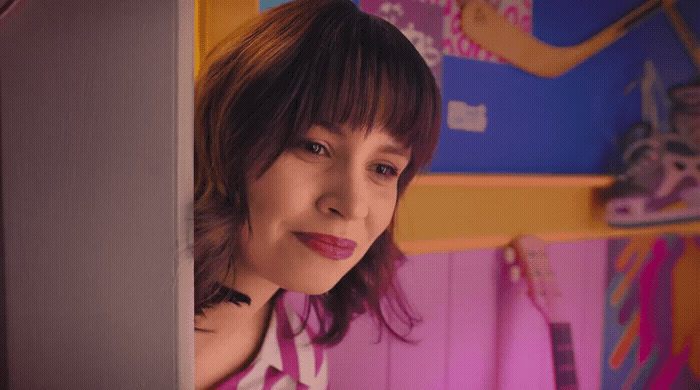 a woman standing in front of a pink wall