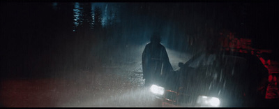 a man standing next to a car in the rain