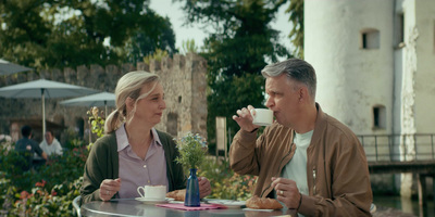 a man and a woman sitting at a table drinking coffee