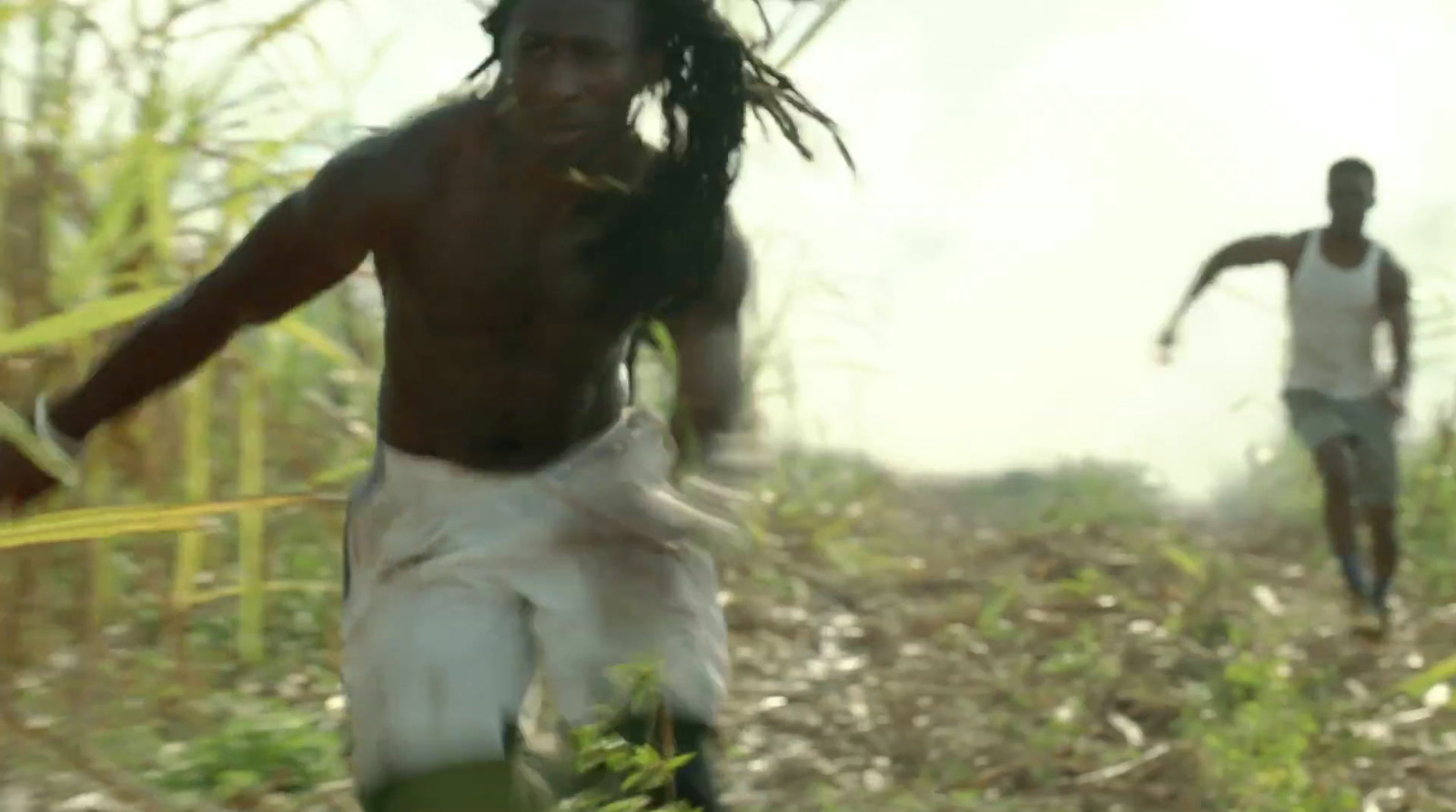 two young men running through a field of tall grass