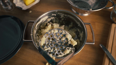 a metal bowl filled with food on top of a wooden table