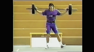 a man holding a barbell in a gym