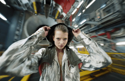 a woman in a silver jacket is standing in a space station