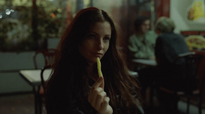 a woman sitting at a table with a banana in her hand