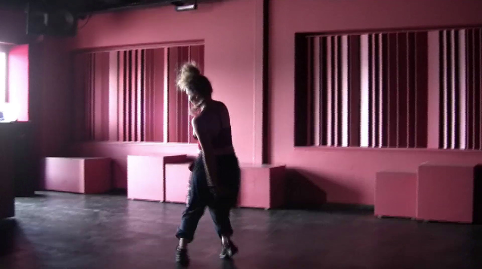 a woman walking in a room with pink walls