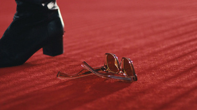 a pair of sunglasses laying on a red carpet