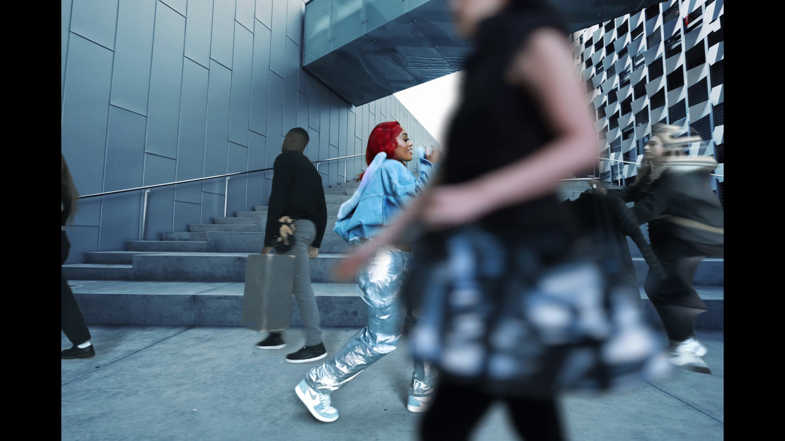 a group of people walking down a sidewalk next to a building