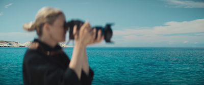 a woman taking a picture of the ocean with a camera