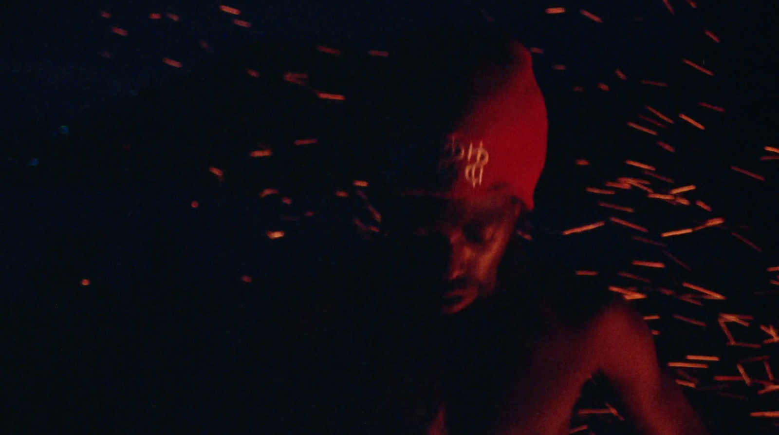 a man standing in the dark with a red hat on