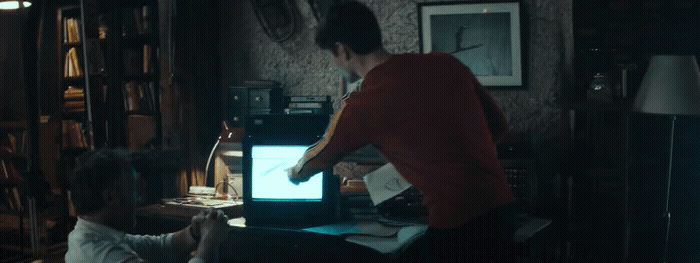 a man and a woman sitting in front of a laptop computer