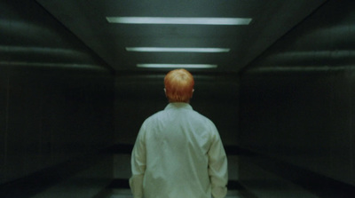 a man with red hair walking down a hallway