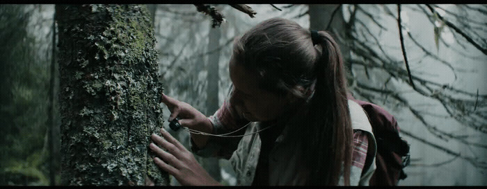 a woman with long hair standing next to a tree