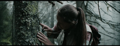 a woman with long hair standing next to a tree