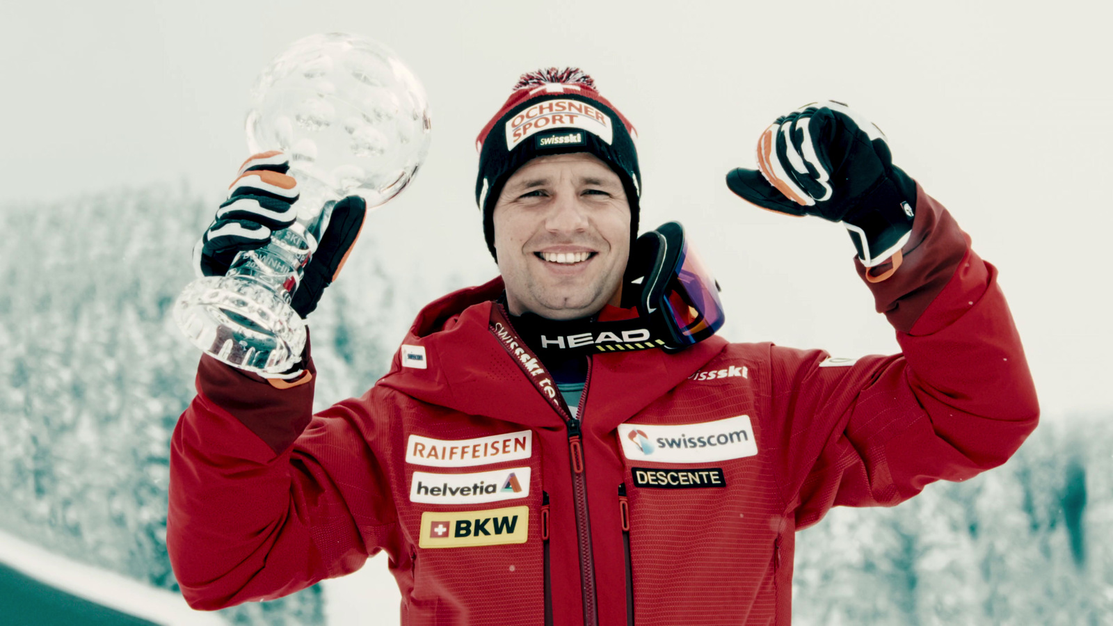 a man in a red jacket holding up a trophy