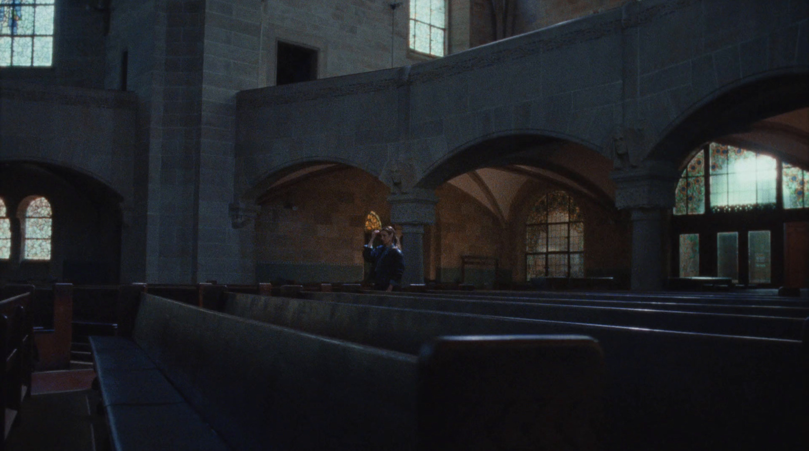 a couple of people standing in a church next to pews