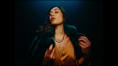 a woman wearing a green coat and a necklace