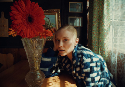 a woman sitting at a table with a vase of flowers