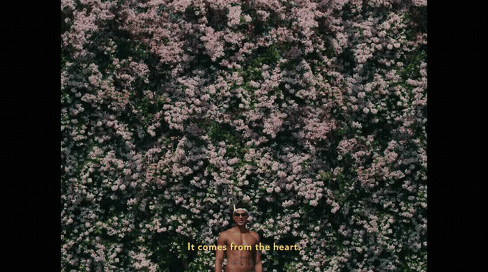 a man standing in front of a wall of flowers