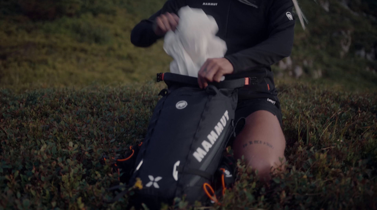 a person sitting in the grass with a bag