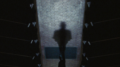 a shadow of a person standing in front of a urinal