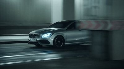 a silver car driving down a street at night