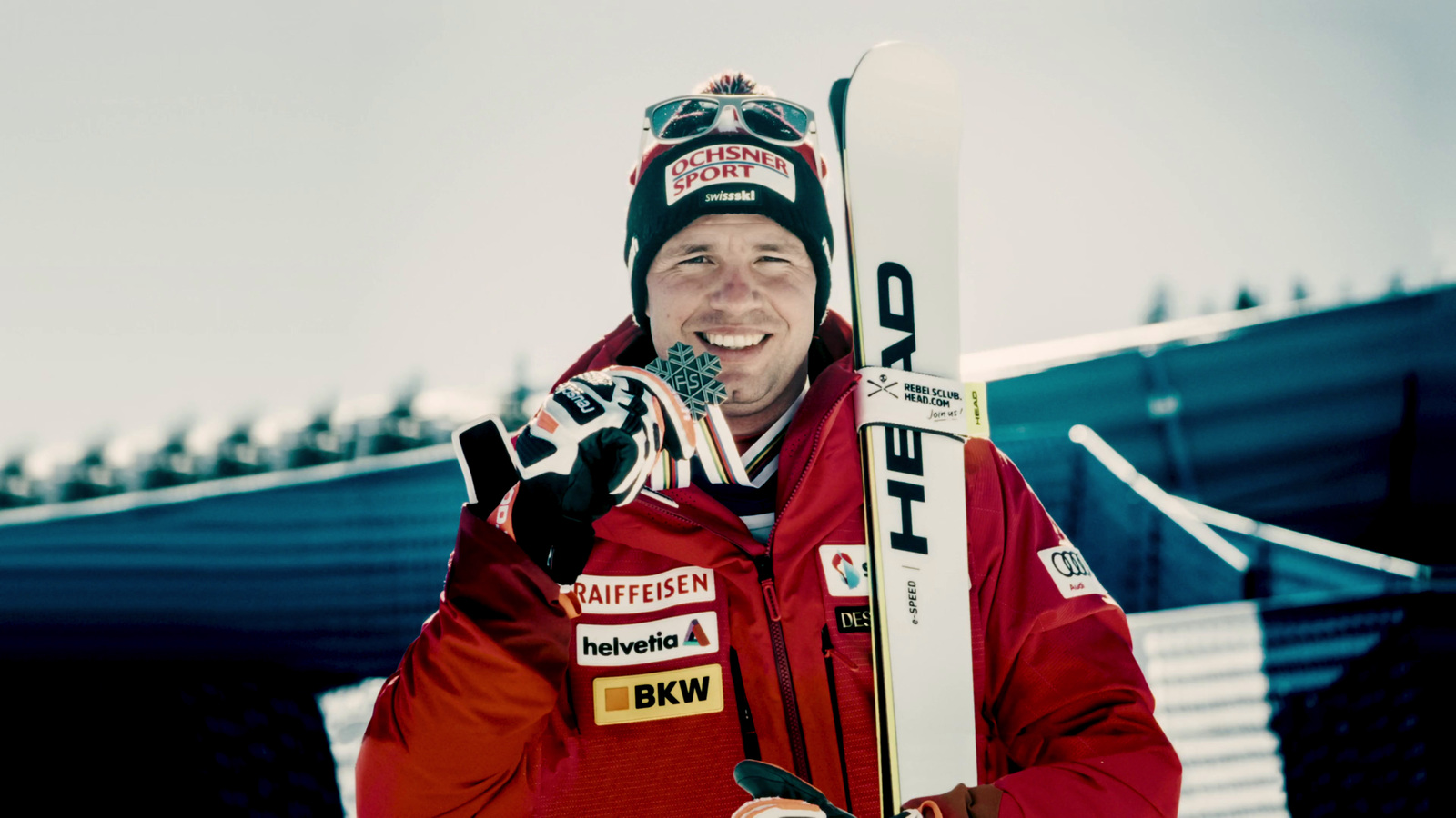 a man in a red jacket holding a pair of skis