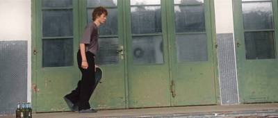 a young man is walking in front of a green door