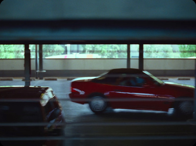 a red car driving through a parking garage