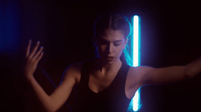 a woman standing in a dark room with a neon light behind her