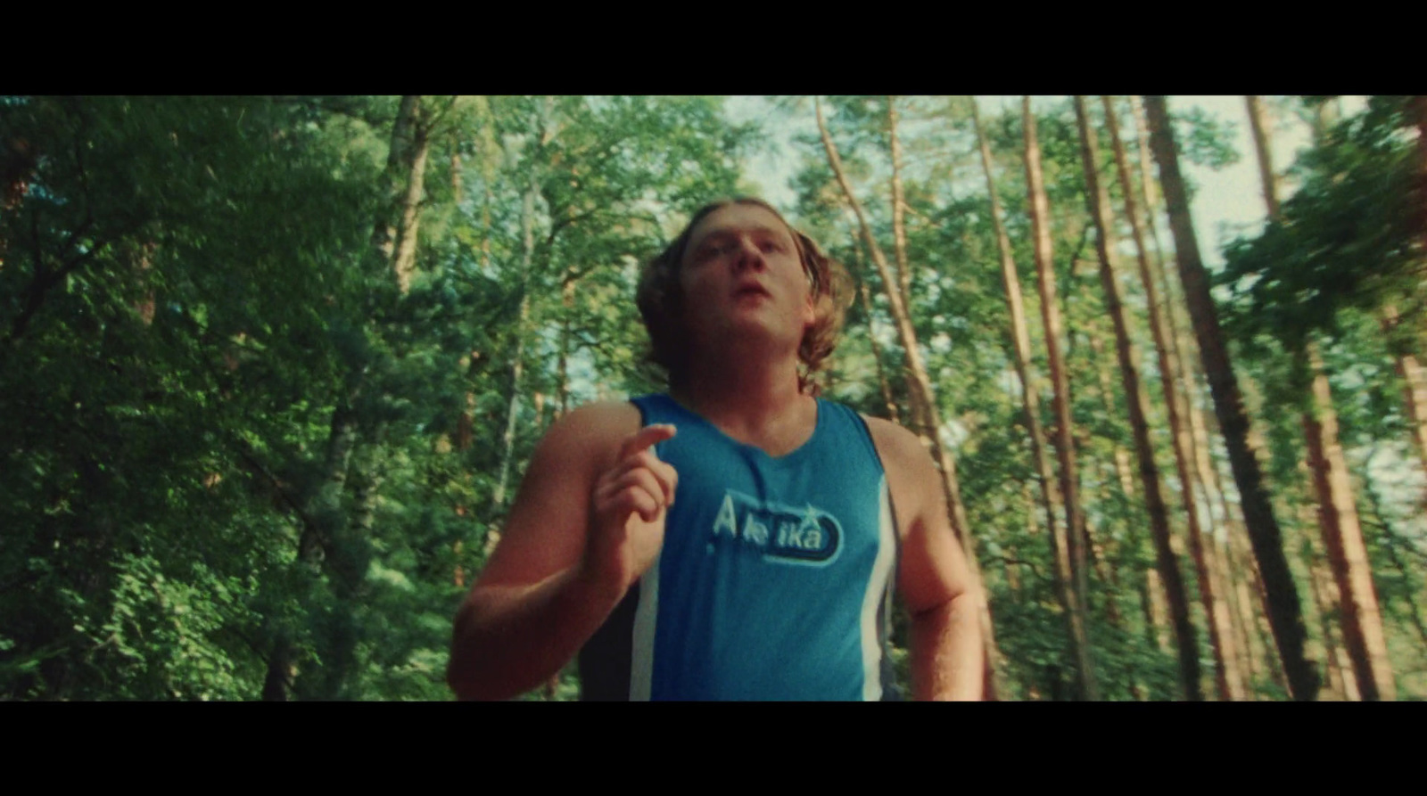 a man in a blue shirt running through a forest