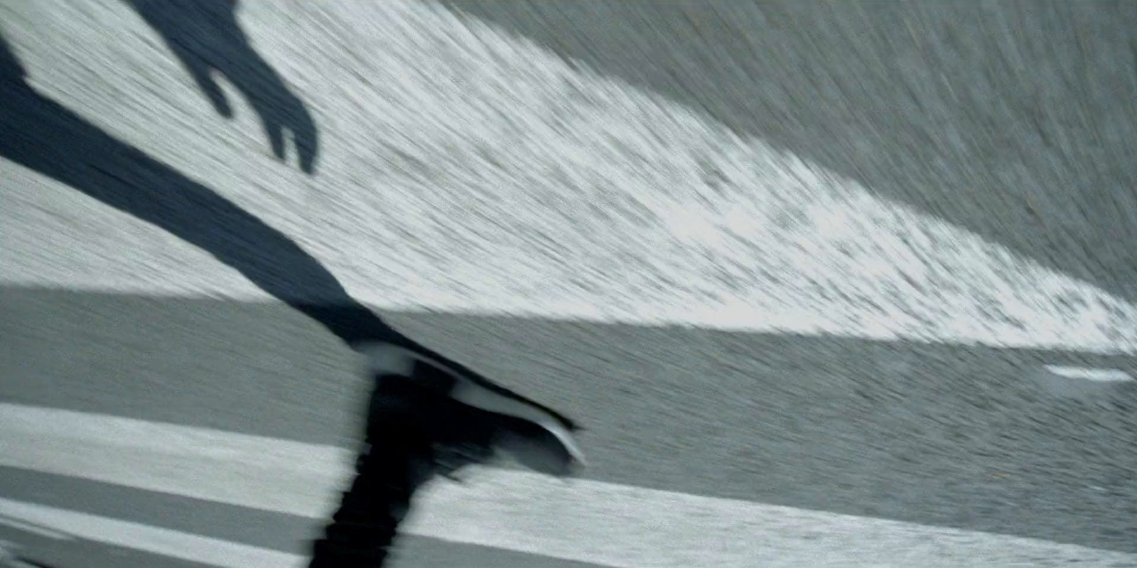 a man riding a skateboard down a street next to a wave