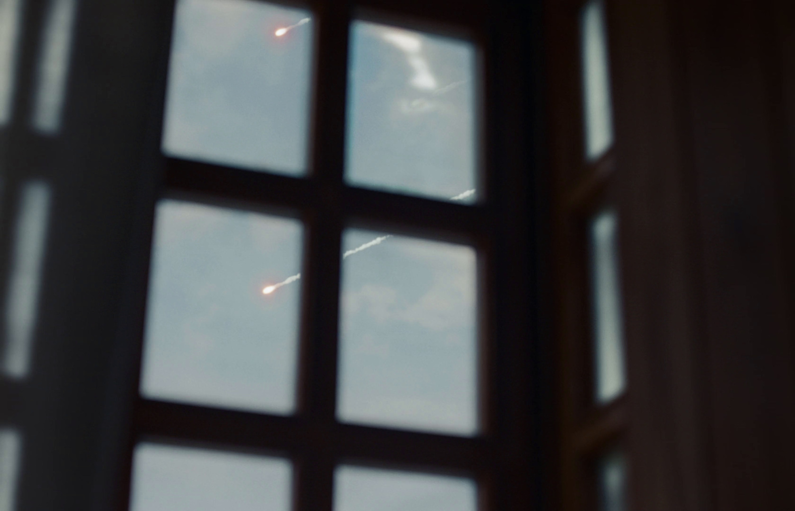 a window with a view of a plane flying in the sky