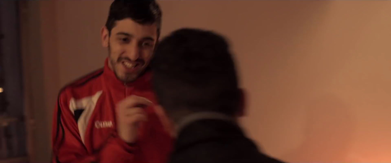 a man in a red jacket is talking to another man