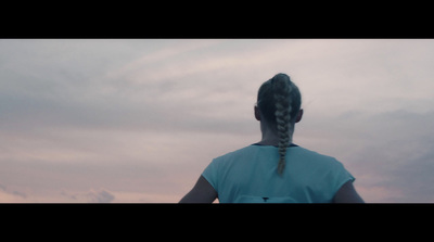 a woman with a braid standing in front of a cloudy sky